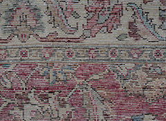 A close-up view of a vintage Persian Kerman runner featuring intricate floral patterns in red.