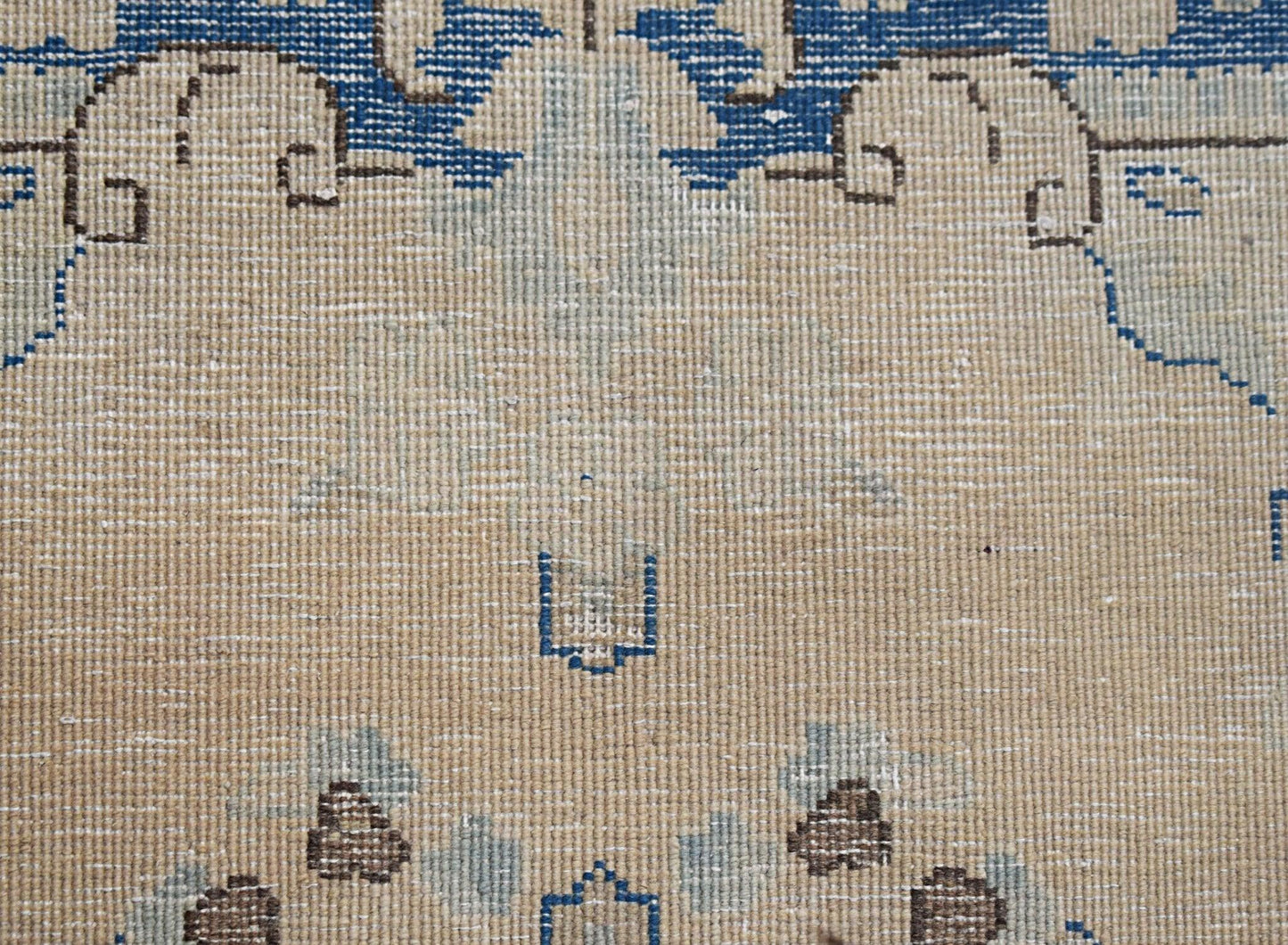 A close-up of a vintage Persian Kerman runner featuring intricate blue and brown floral motifs.