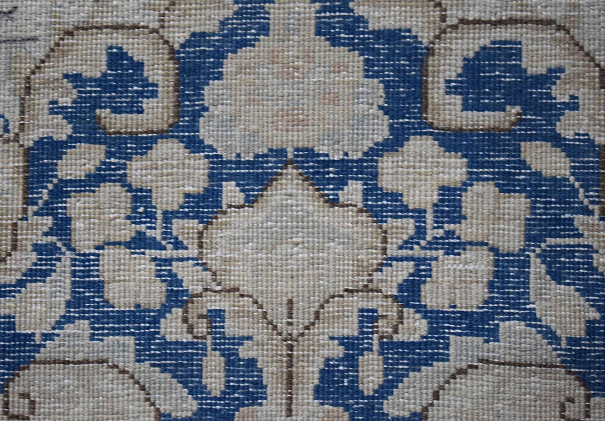 A close-up of a vintage Persian Kerman runner featuring intricate floral patterns in blue and cream.