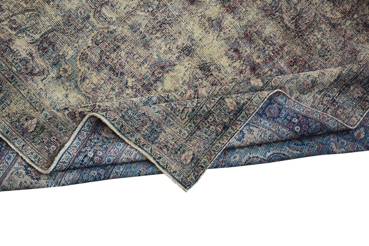 An antique Persian Kerman rug featuring a detailed floral medallion pattern in blue and red tones.