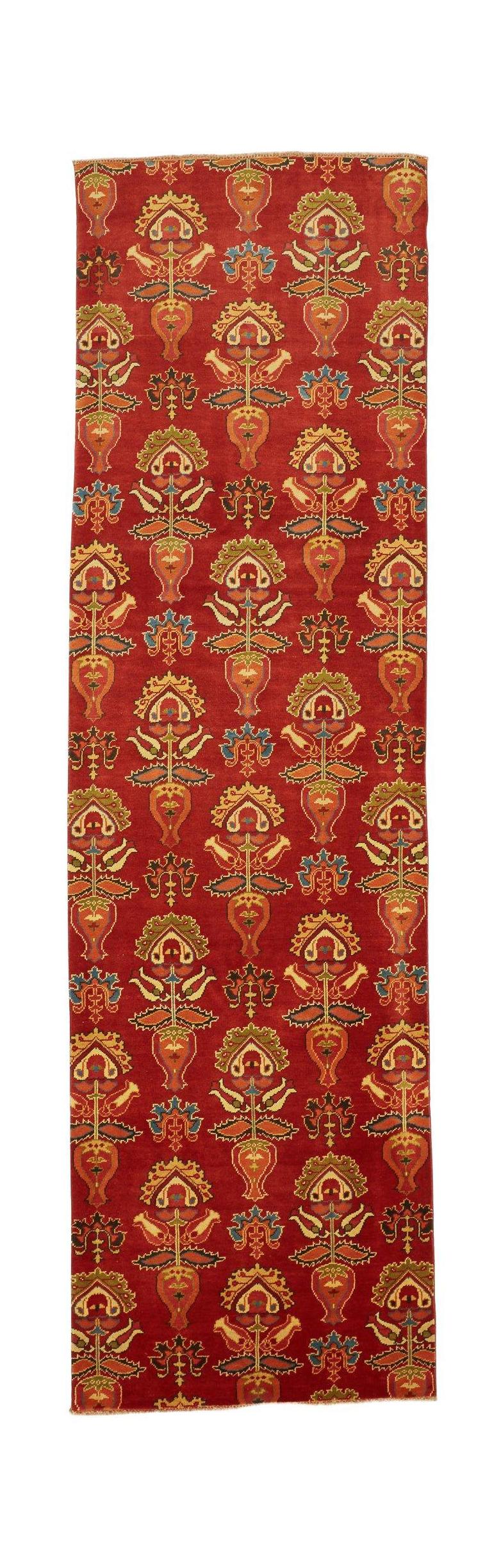 Handmade Afghan Chobi runner rug featuring a repeating floral motif on a red wool background.