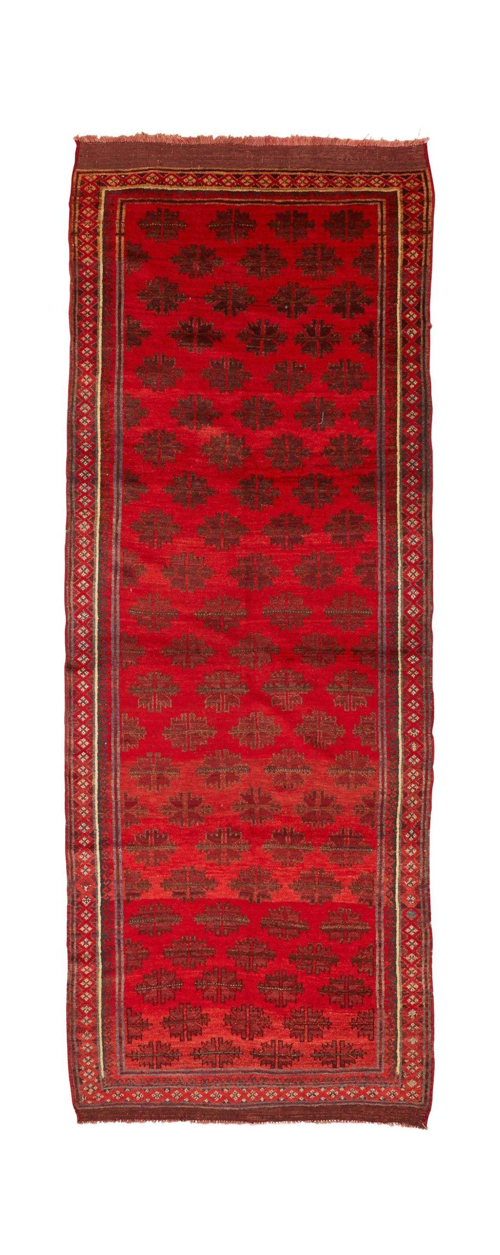 A vintage handmade Afghan Baluch runner featuring a repeating dark geometric pattern on a red field.
