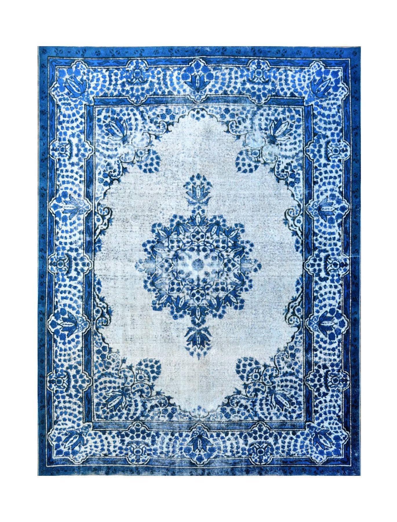A vintage Persian Kerman rug featuring a central blue floral medallion on a light field.