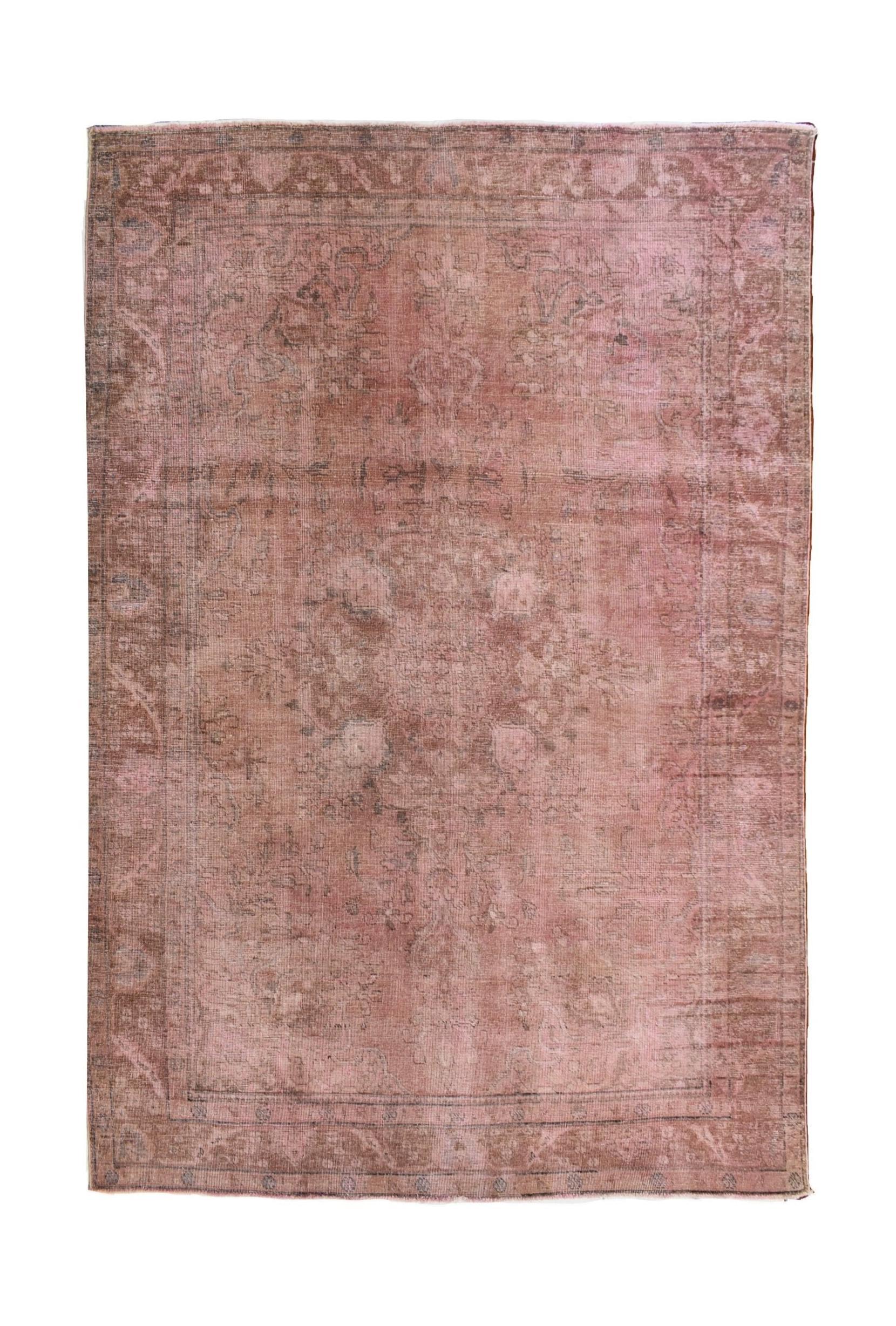 A vintage Persian Kerman rug featuring a faded pink and brown floral medallion design.