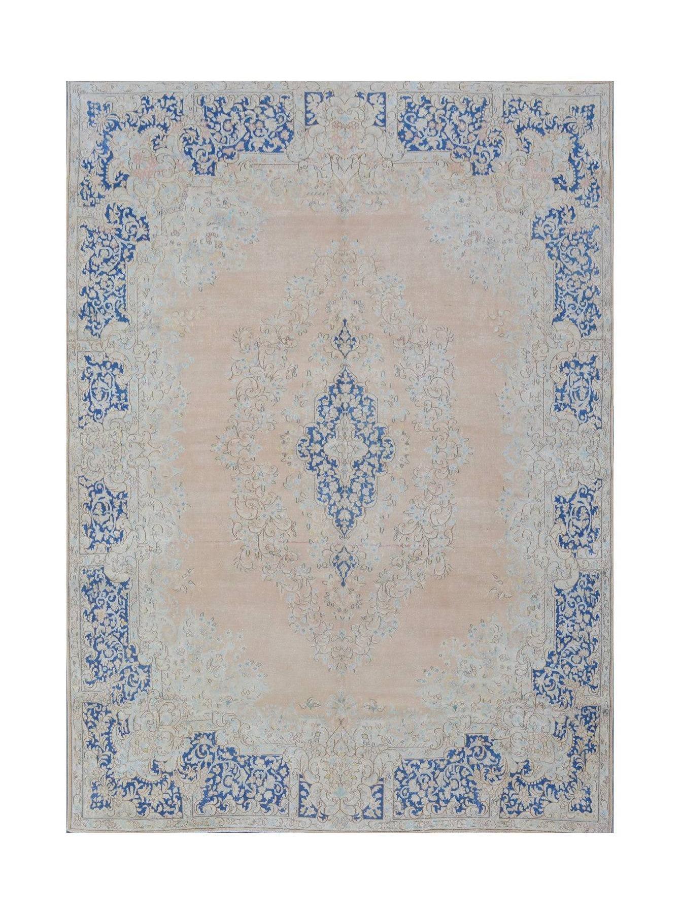 A vintage Persian Kerman rug featuring a central blue floral medallion on a soft peach background.