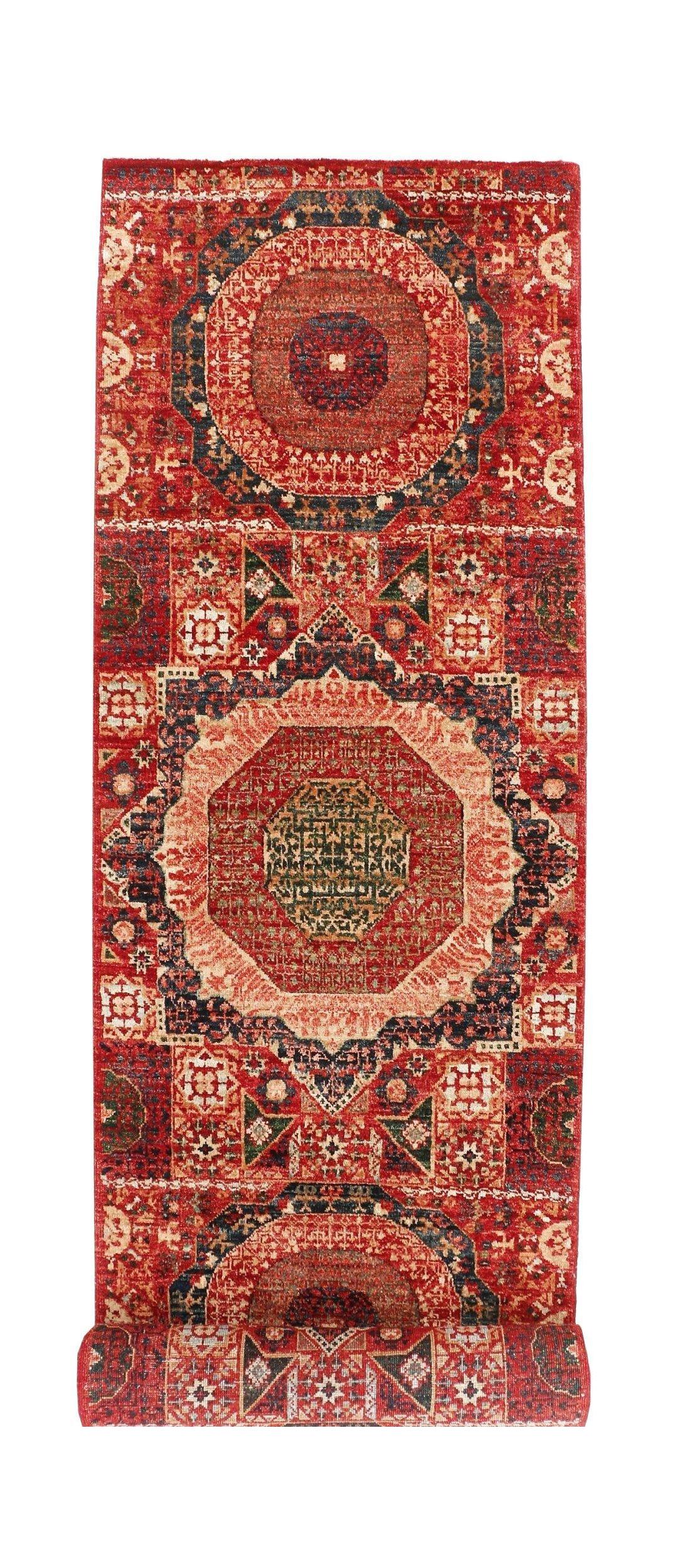 A handmade Afghan Chobi runner rug featuring intricate red, blue, and green geometric medallions.