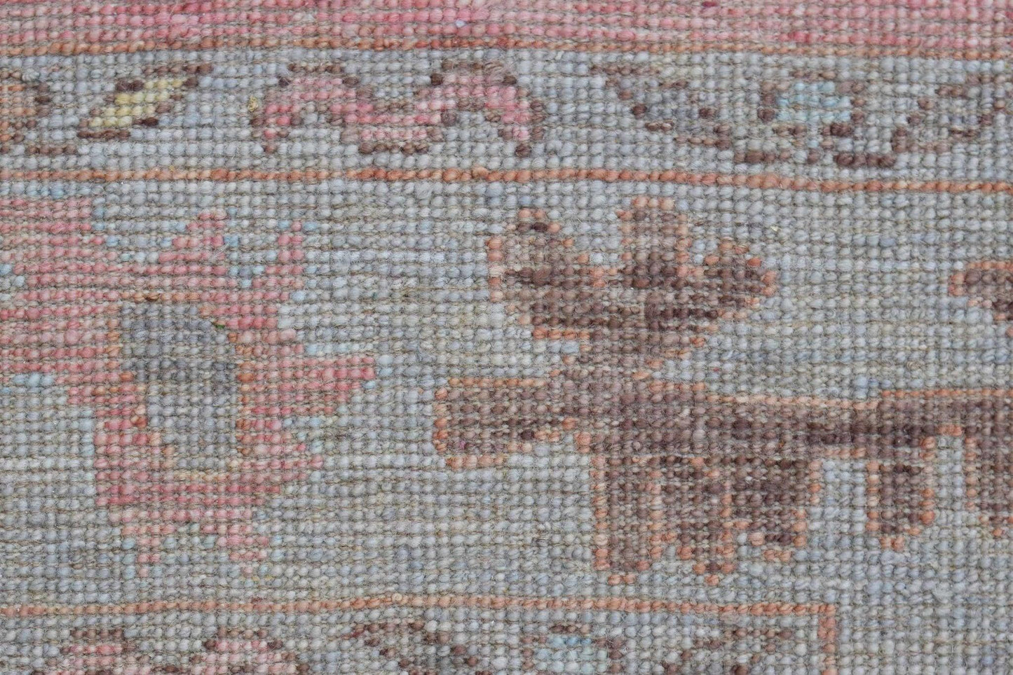 A close-up view of a handwoven wool runner rug featuring a transitional floral pattern in soft tones.