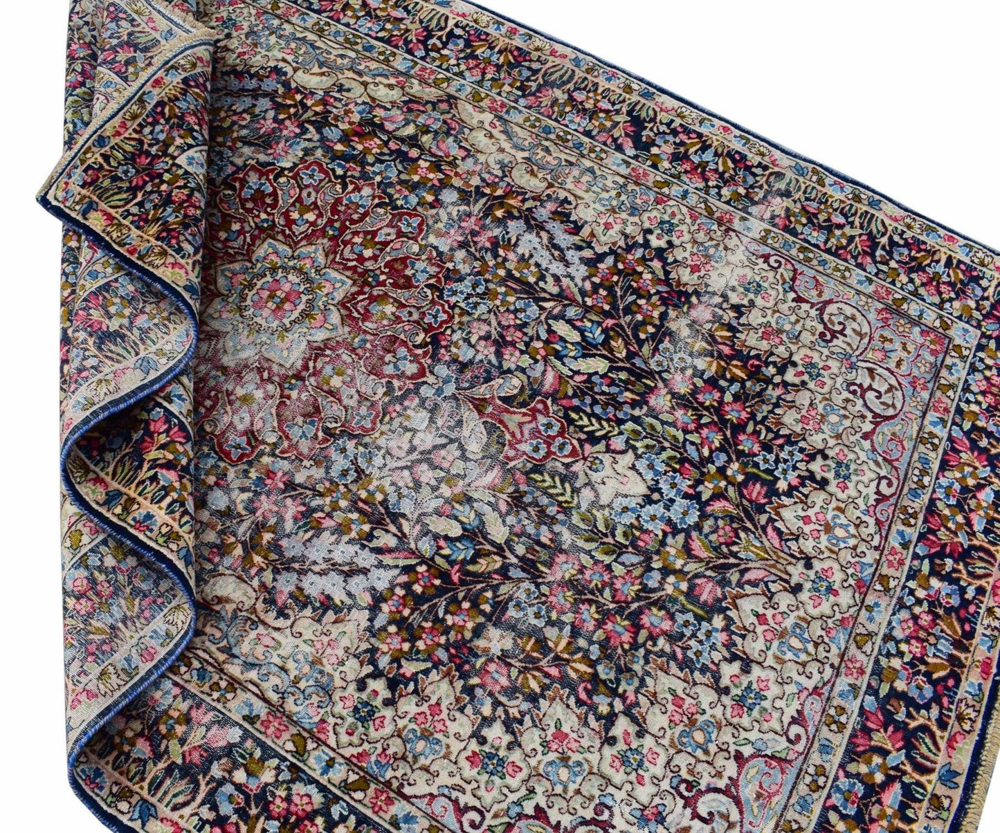 A vintage Persian Kerman rug featuring an intricate floral medallion design in blue and red tones.