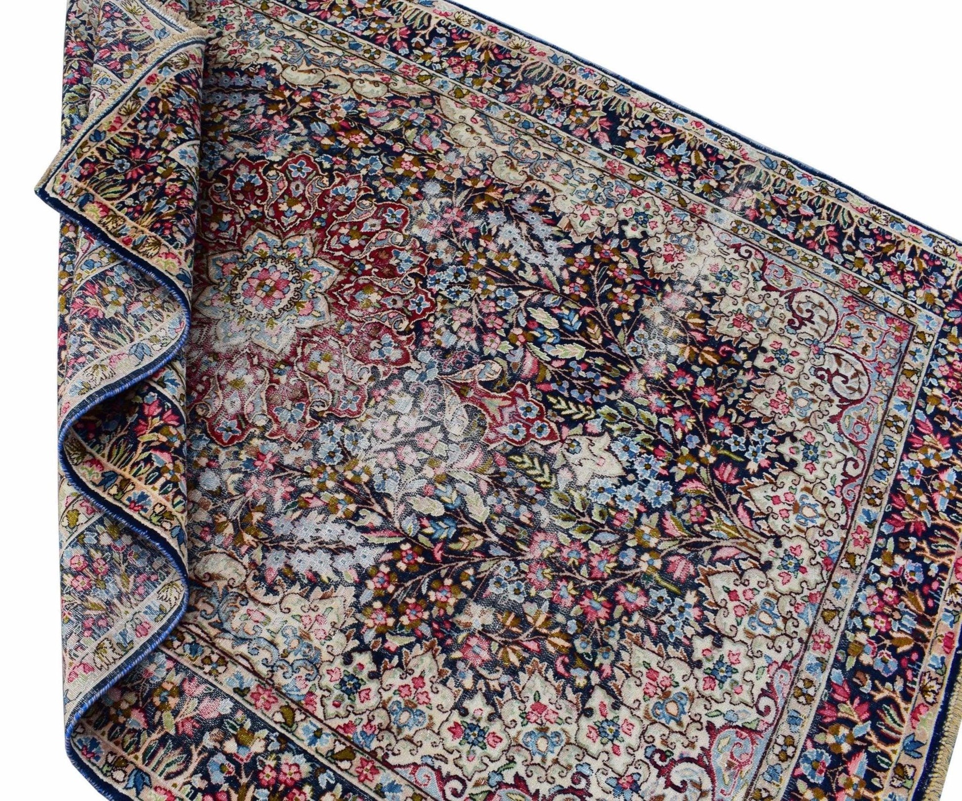 A vintage Persian Kerman rug featuring an intricate floral medallion design in blue and red tones.