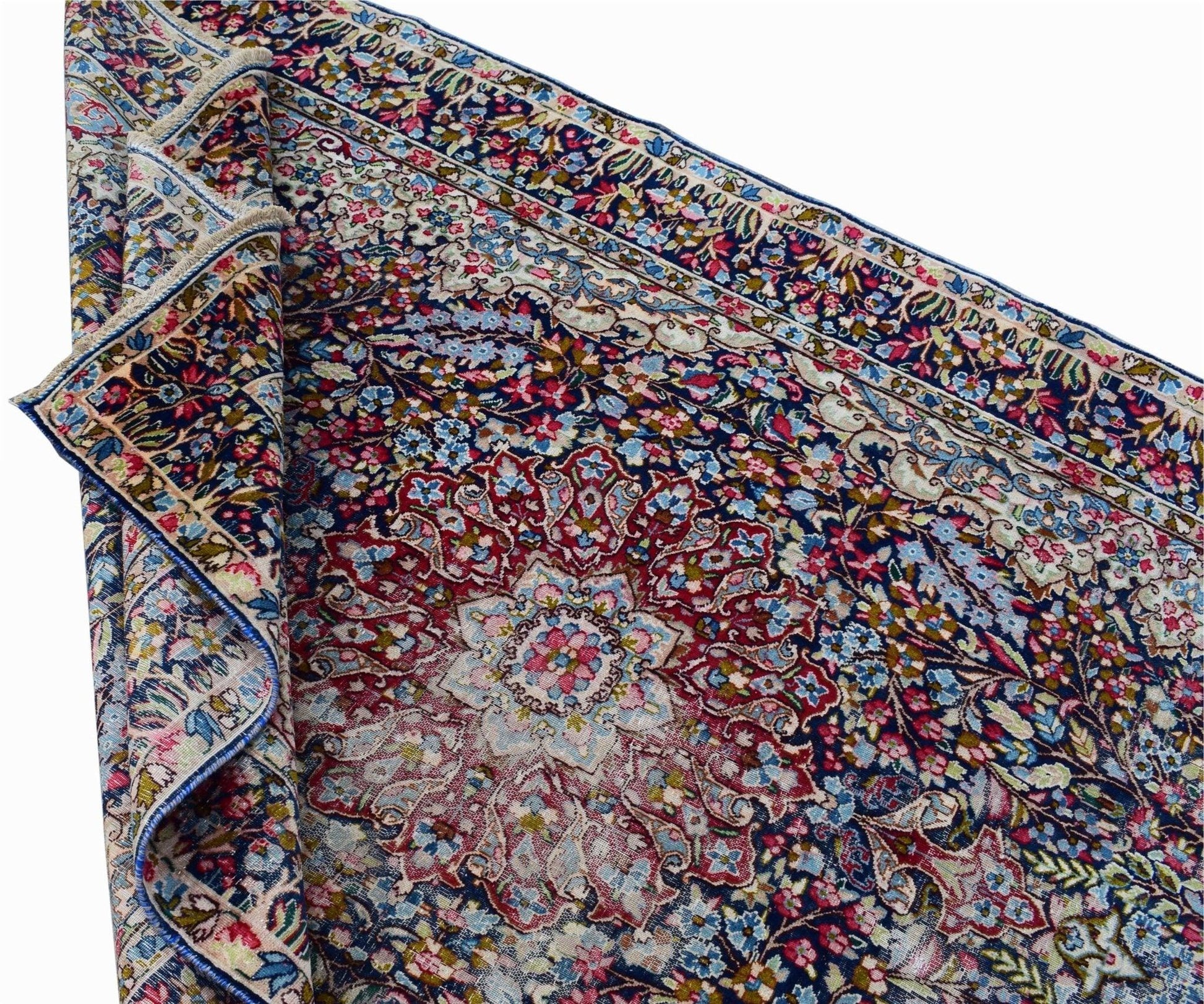A vintage Persian Kerman rug featuring an intricate floral medallion design in deep blue and red.