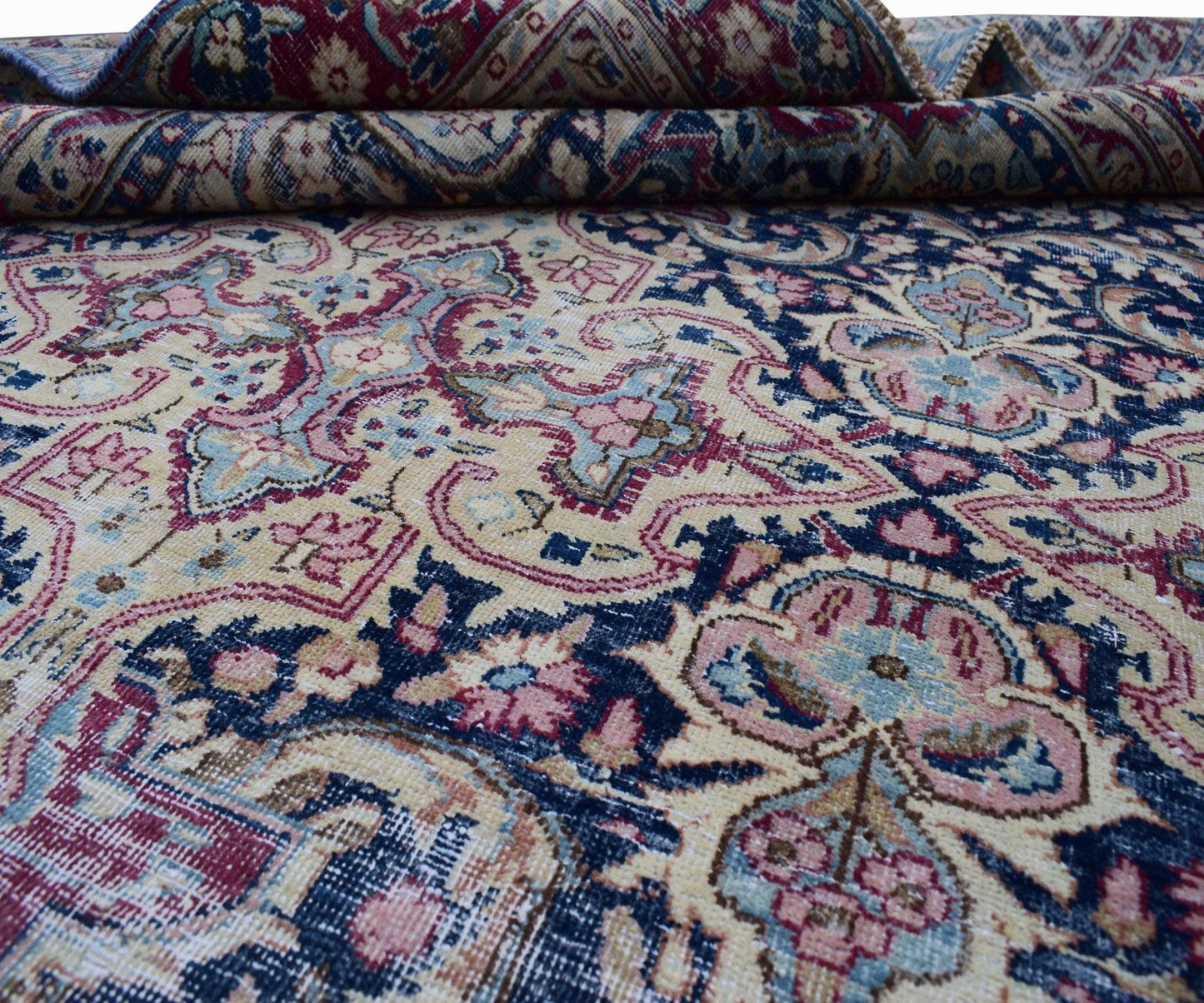 A vintage Persian Kerman rug featuring an intricate floral medallion pattern in blue and pink.