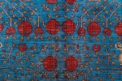 A handwoven Afghan Balkh rug featuring a repeating pattern of red pomegranate motifs on a blue field.