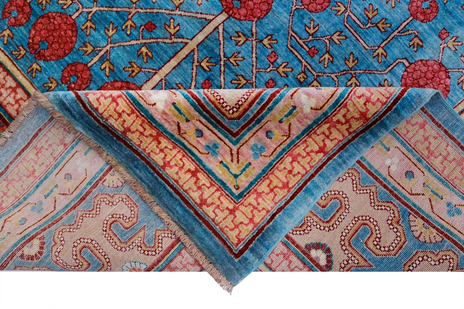 A handwoven Afghan Balkh rug featuring a blue field with red floral motifs and a folded corner.