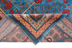 A handwoven Afghan Balkh rug featuring a blue field with red floral motifs and a folded corner.