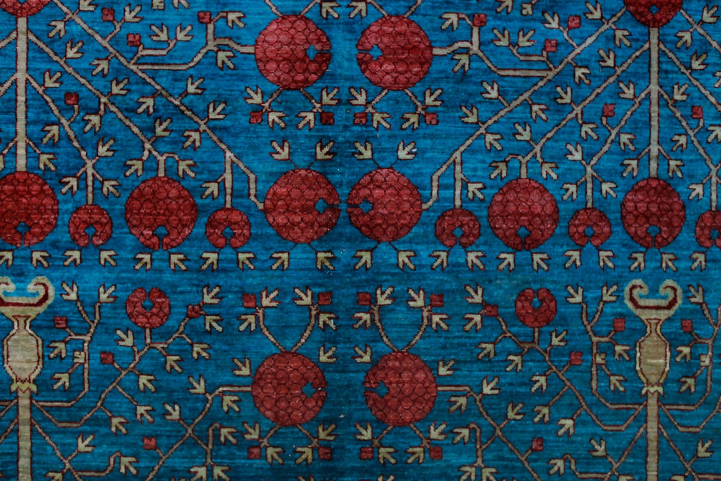 A handwoven Afghan Balkh rug featuring a repeating pattern of red pomegranate motifs on a blue field.