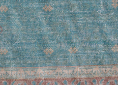 A close-up of a handwoven Afghan Balkh rug featuring a blue field with subtle geometric patterns.