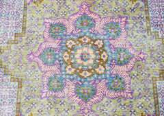 An Afghan Balkh rug featuring a central floral medallion in shades of purple, blue, and gold.