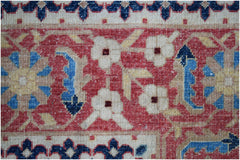 A close-up of an Afghan Balkh rug featuring a red field with floral motifs and blue accents.