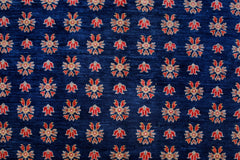 An Afghan Balkh rug featuring a repeating floral pattern in red and cream on a deep blue background.