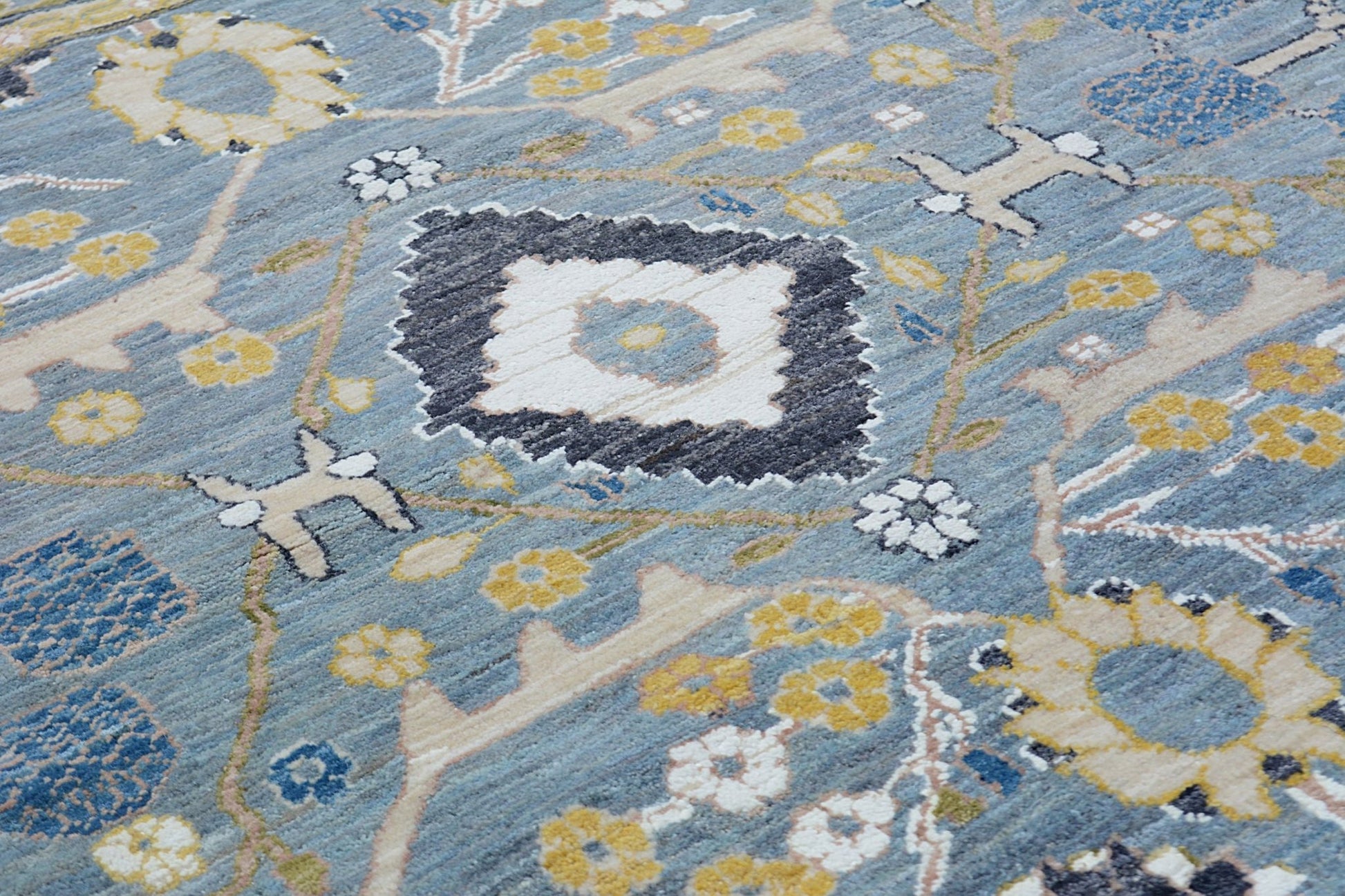 Handmade Afghan Balkh rug featuring a traditional floral pattern in blue, yellow, and cream tones.