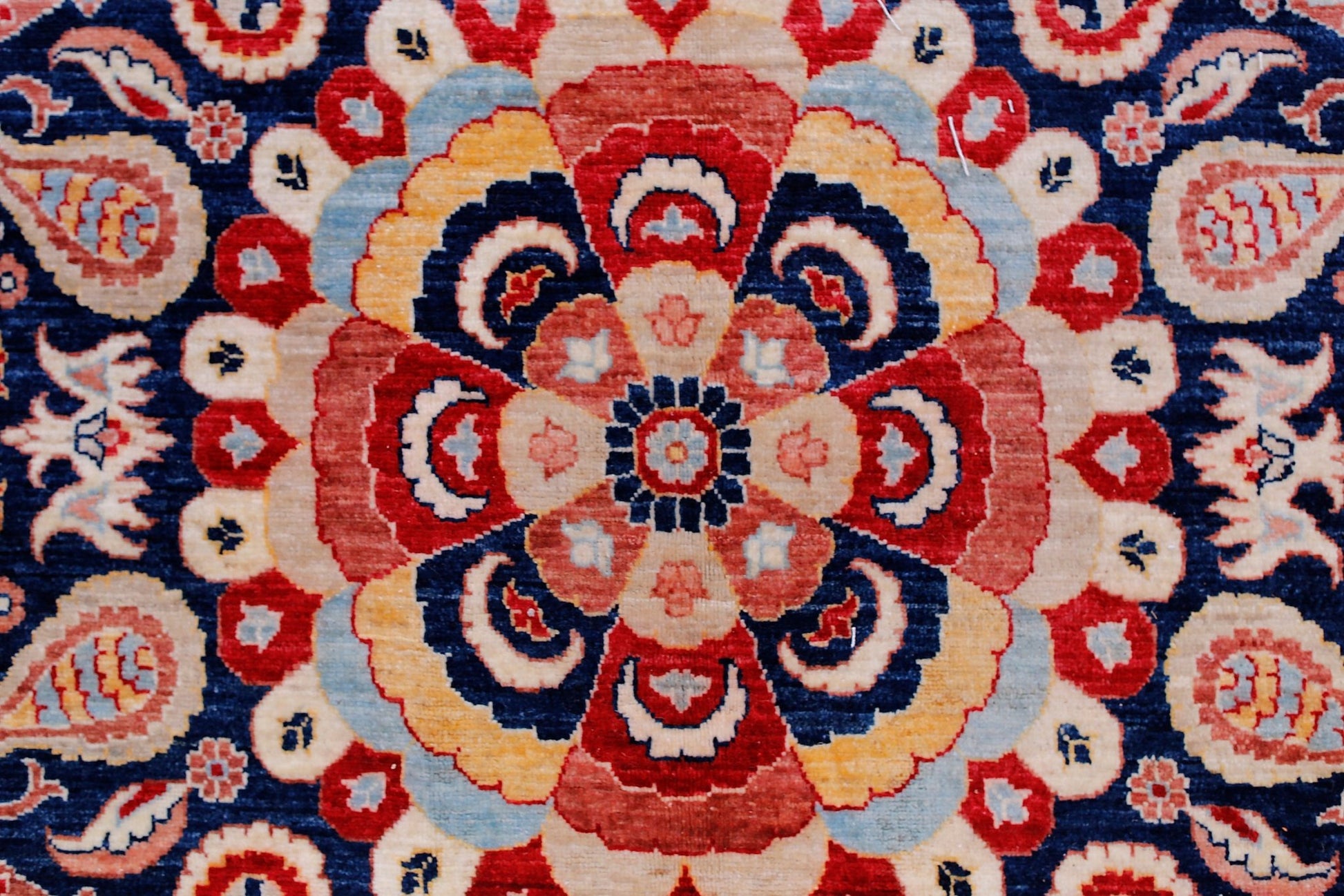 A handwoven Afghan Balkh rug featuring a detailed floral medallion in red, blue, and cream tones.