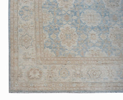 A handmade Afghan Balkh rug featuring a traditional floral pattern in soft blue and beige tones.