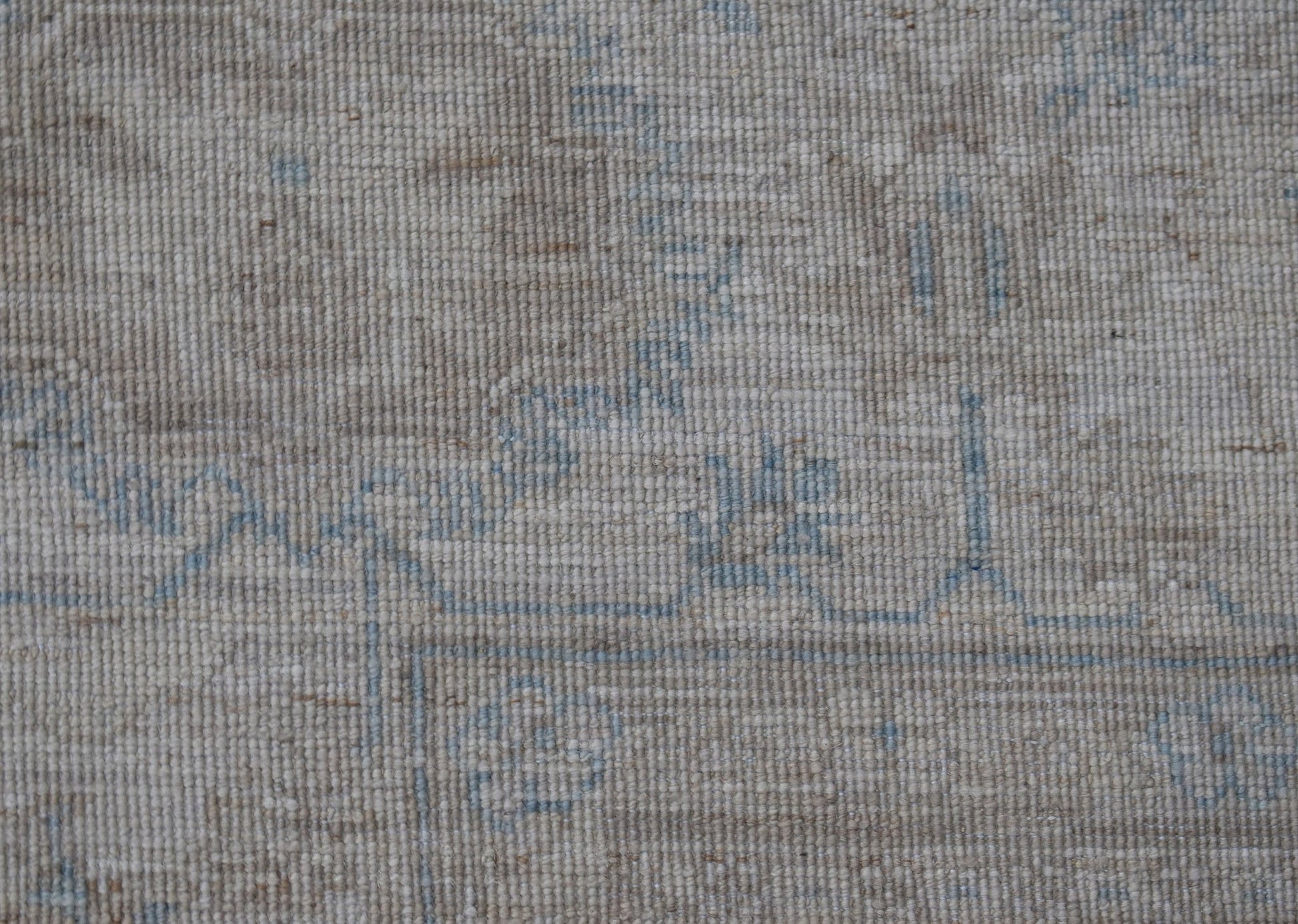 A close-up view of a handwoven Afghan Balkh rug featuring a neutral beige pattern with blue accents.