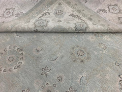 A handmade Afghan Balkh rug featuring a light blue and grey floral pattern with a folded corner.