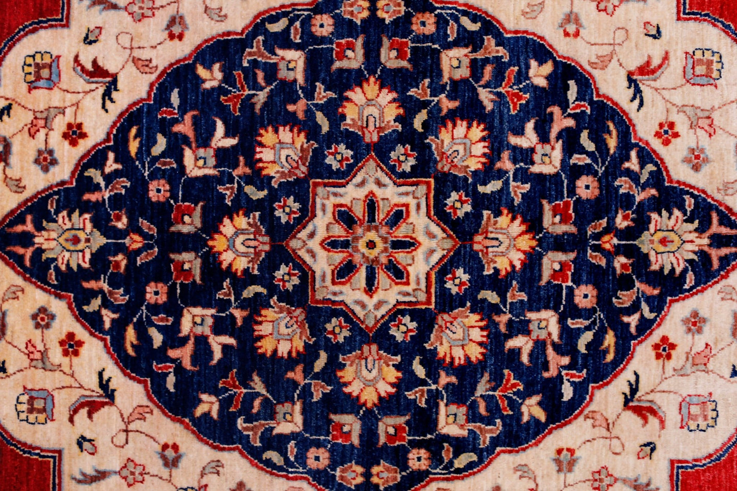 A handwoven Afghan Balkh rug featuring a central floral medallion on a deep blue field.