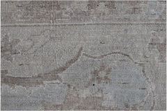 A close-up of a handwoven Afghan Balkh rug featuring a neutral, distressed floral pattern.