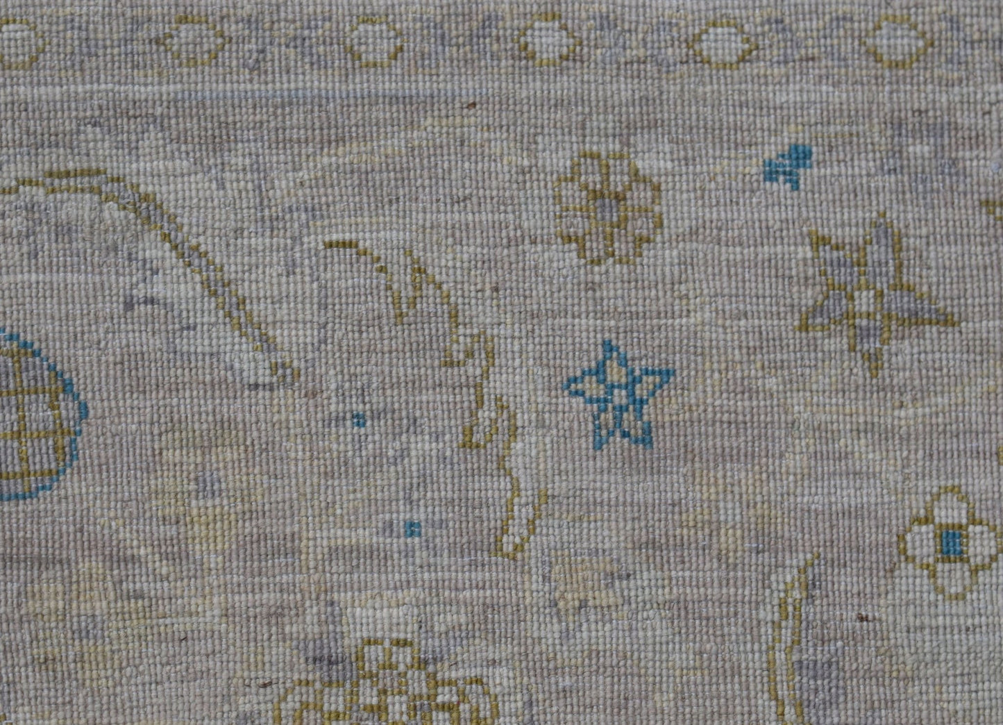 A handwoven Afghan Balkh rug featuring a light beige field with small blue and yellow star motifs.