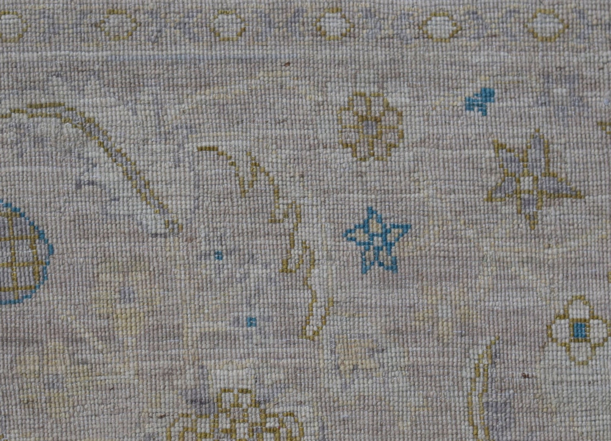 A handwoven Afghan Balkh rug featuring a light beige field with small blue and yellow star motifs.
