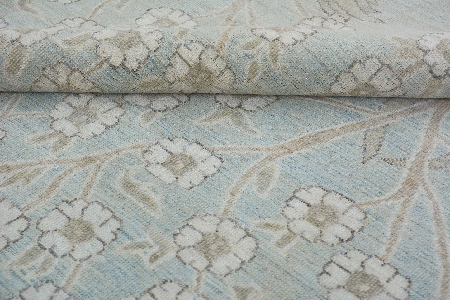 A handmade Afghan Balkh rug featuring a light blue field with a beige floral vine pattern.
