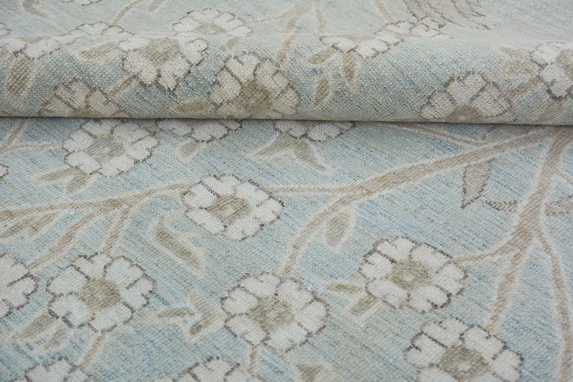A handmade Afghan Balkh rug featuring a light blue field with a beige floral vine pattern.