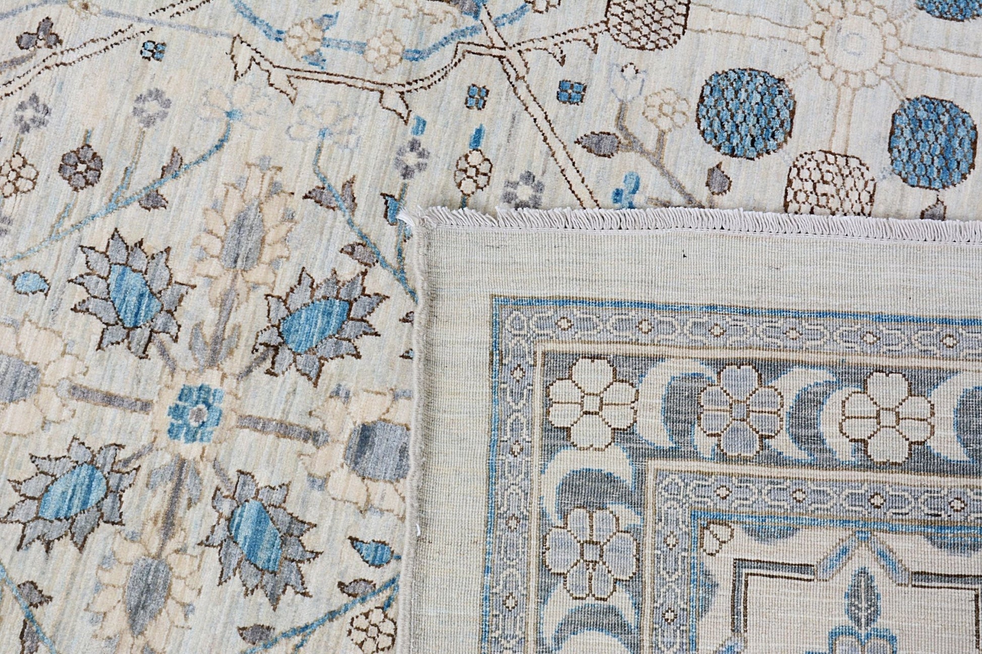 A handmade Afghan Balkh rug featuring a traditional floral pattern in blue, grey, and cream tones.