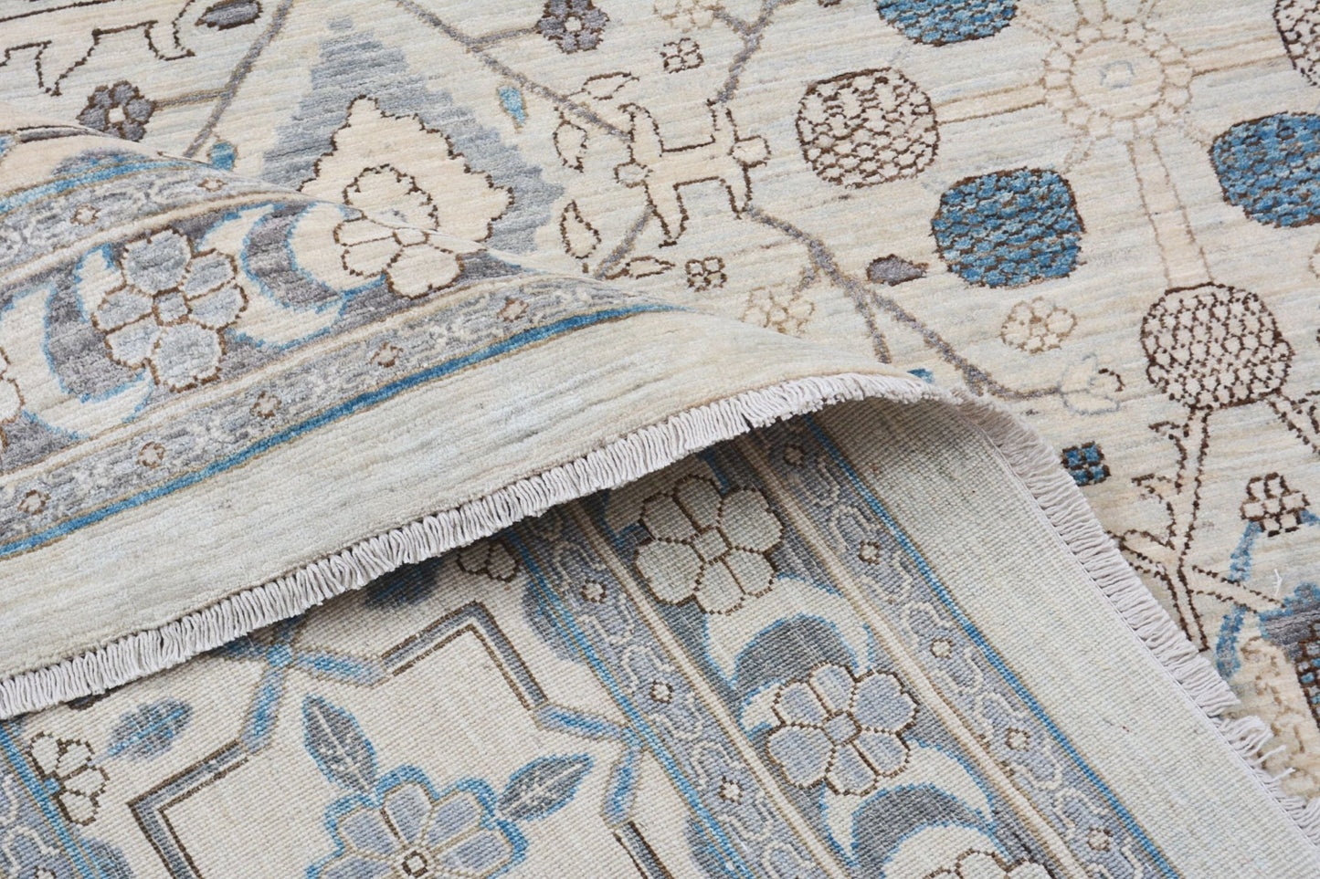 A handmade Afghan Balkh rug featuring a traditional floral pattern in blue, grey, and cream tones.