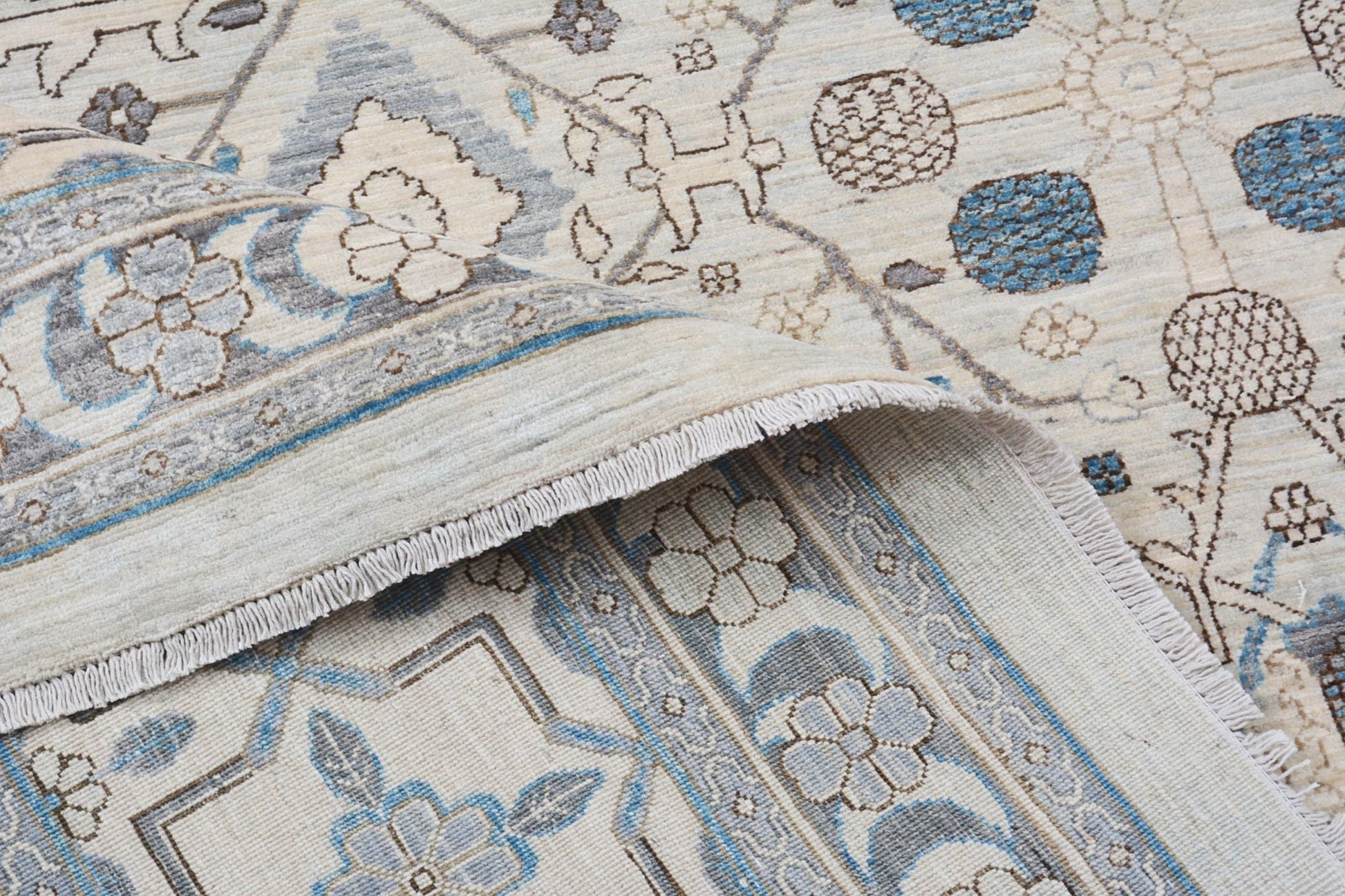 A handmade Afghan Balkh rug featuring a traditional floral pattern in blue, grey, and cream tones.