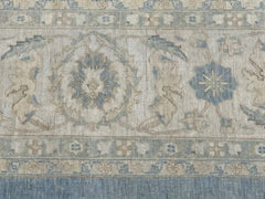 A handmade Afghan Balkh rug featuring a traditional floral pattern in muted blue and beige tones.