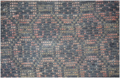 A close-up of a handmade Afghan Baluch rug featuring a geometric pattern in dark and red wool.