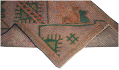 A handmade Afghan Baluch rug featuring geometric patterns in muted pink, green, and orange tones.
