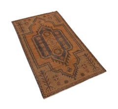 A handmade Afghan Baluch rug featuring a geometric medallion pattern in shades of brown and rust.