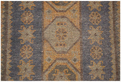 A handmade Afghan Baluch rug featuring geometric patterns in shades of brown and orange.