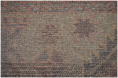 A close-up of a handmade Afghan Baluch wool rug featuring geometric patterns in earthy tones.