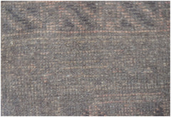 A close-up view of a handmade Afghan Baluch wool rug featuring a dark, textured geometric pattern.