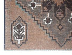 A handmade Afghan Baluch rug featuring geometric patterns in brown and cream wool.