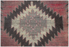 A handmade Afghan Baluch rug featuring a central diamond motif in shades of red, brown, and tan.