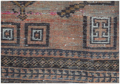 A close-up of a handmade Afghan Baluch rug featuring geometric patterns in orange and dark brown.