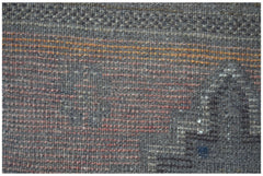 A close-up of a handmade Afghan Baluch rug featuring a dark wool texture with subtle orange accents.