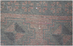 A close-up of a handmade Afghan Baluch rug featuring geometric patterns in brown and orange wool.