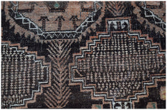A handmade Afghan Baluch wool rug featuring intricate geometric patterns in black and muted orange.